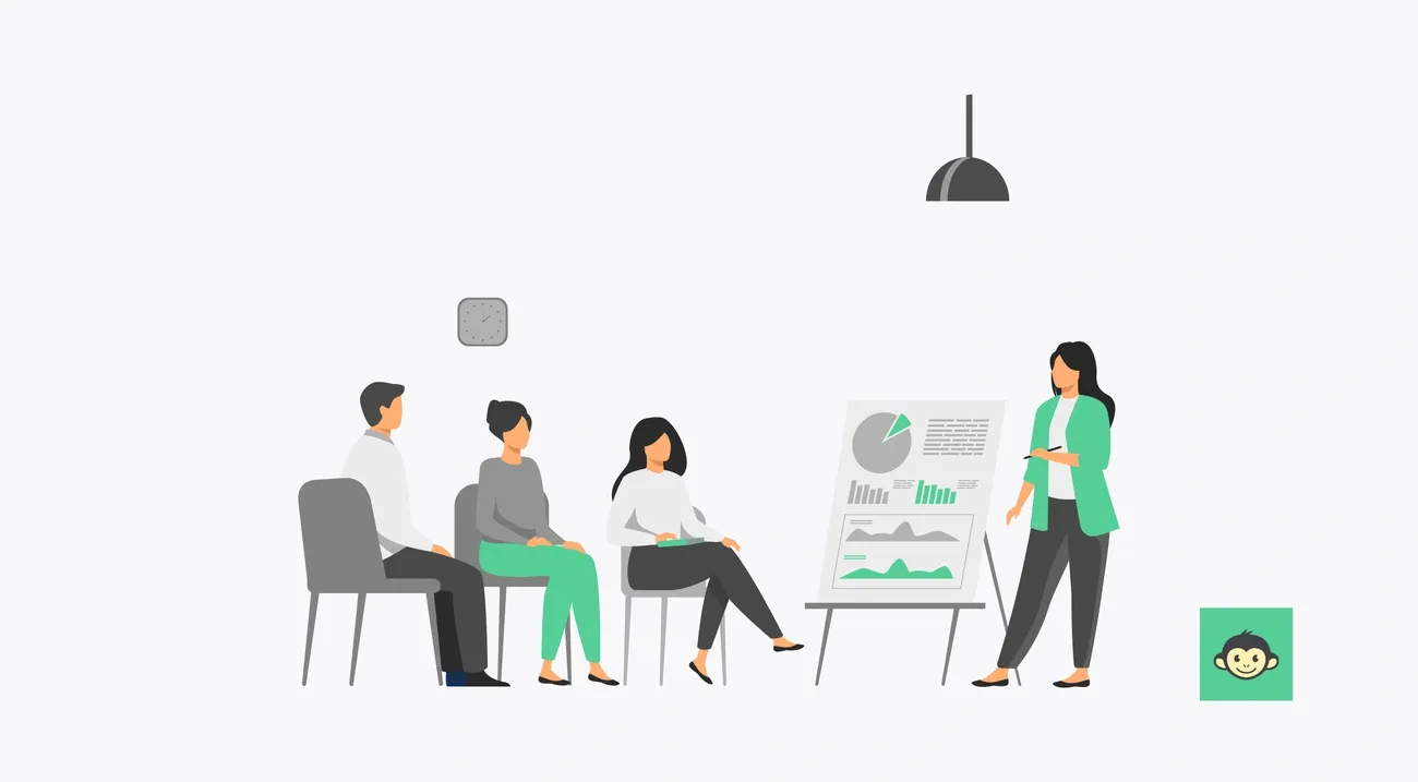 A woman in green coaching three seated people using charts and graphs on a presentation board in a meeting room.